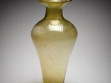 un vase en verre jaune posé sur une surface blanche