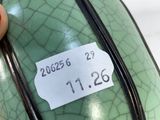 someone is holding a green vase with a tag on it