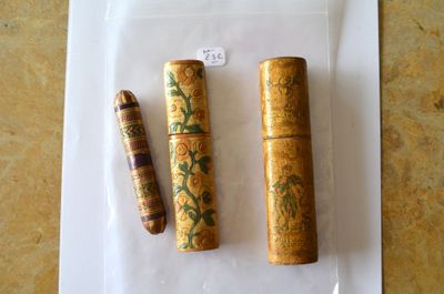 trois tubes en bois posés sur une feuille de papier, elle-même posée sur une table