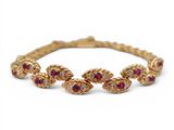 un gros plan sur un bracelet en or orné de pierres rouges et blanches