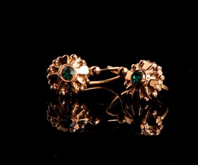 un gros plan sur une paire de boucles d'oreilles en or ornées d'émeraudes
