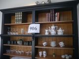 a black bookcase with a lot of cups and saucers on it