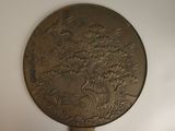 a bronze plate with a tree and birds on it