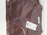 une chemise marron dans un sac en plastique posé sur une surface blanche