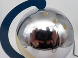 someone is taking a picture of a silver object with their reflection in it