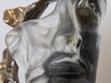 sculpture of a woman ' s face with a leaf in her hair