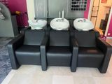 quatre chaises noires sur lesquelles sont posés des lavabos blancs, dans une pièce