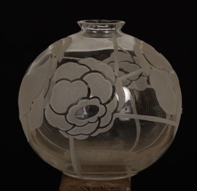 un vase en verre orné d'une fleur, posé sur un socle en bois