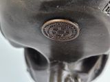 a metal skull with a coin in it ' s mouth