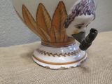 a vase with a bird on it sitting on a table