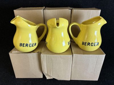 trois pichets jaunes posés sur une boîte en carton, elle-même posée sur une surface noire