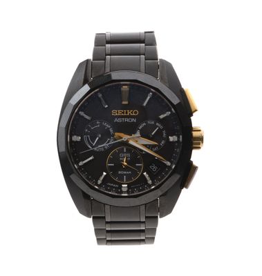 La montre est noire et dorée, avec un cadran noir et des aiguilles dorées.