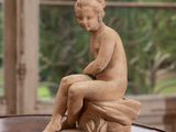a statue of a boy sitting on top of a wooden table