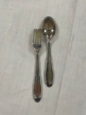 deux cuillères en argent et une fourchette posées sur une nappe blanche