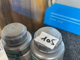 two bottles of paint sitting on a table next to a bottle of glue