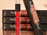 trois gloss sont posés sur une pile de livres