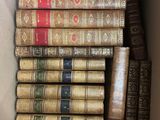 several old books are stacked in a box on a table