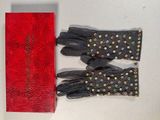 pair of black leather gloves and a red box on a table