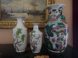 trois vases posés sur une table à côté d'un tableau