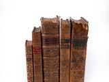several old books are stacked on top of each other on a white surface