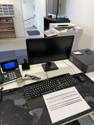 un bureau sur lequel se trouvent un ordinateur, une imprimante, un téléphone et d'autres objets