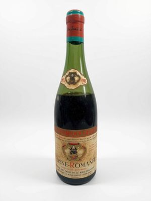 une vieille bouteille de vin posée sur une surface blanche