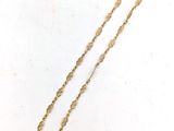 gros plan d'un collier en or sur une surface blanche