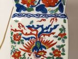 a blue and white vase with red flowers and a bird on it