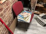 a red chair that is next to a pile of books