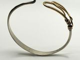 a close up of a silver cuff with a gold snake on it