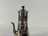 silver plated coffee pot with a black handle on a white surface