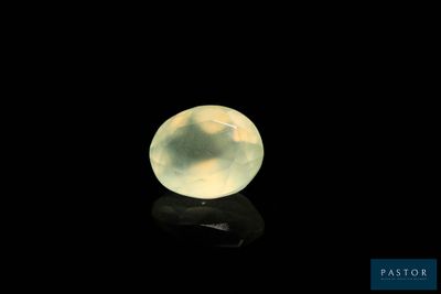 a close up of a yellow jade ball on a black surface