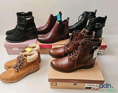 trois paires de bottes sont posées sur des cartons, sur une table
