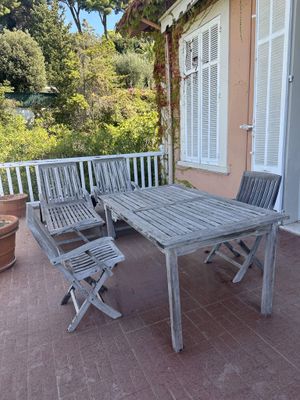 a wooden table and chairs on a patio next to a potted plant