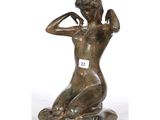 l'image d'une statue de bronze représentant une femme assise sur un rocher
