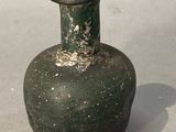 a small green vase sitting on a white surface