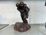 une statue représentant un footballeur tenant un ballon, posée sur une table en verre