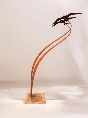 une sculpture en métal représentant deux oiseaux, posée sur un socle en bois