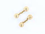 une paire de boucles d'oreilles en forme de boules dorées sur fond blanc