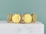 a close up of a gold coin bracelet on a marble block
