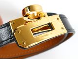 someone is holding a black and gold bracelet with a gold buckle