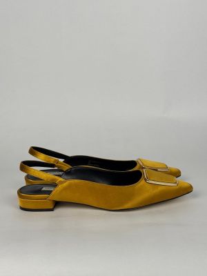 une paire de chaussures jaunes posées sur une surface blanche, avec un fond blanc