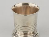 a silver cup on a stand on a white surface