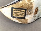 a close up of a white and gold shoe with a label on it