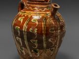 a brown and green vase sitting on a gray surface