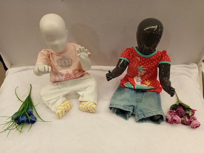 two dolls sitting next to each other on a bed