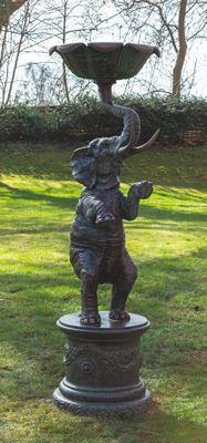 une statue d'éléphant posée sur un socle dans l'herbe