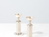 a pair of silver candlesticks sitting on top of a white table