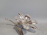 une broche en argent en forme de fleur, ornée d'une feuille