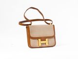 beige and brown handbag with a gold h on the front